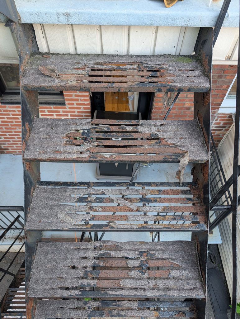 Rusty corroded outdoor metal fire escape stairs with peeling paint and gaps between the treads  Bricopro  Bricopro
