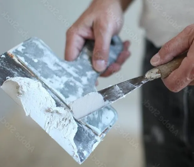 Person smoothing plaster onto a wall with a putty knife in a trench of drywall joint compound  Bricopro  Bricopro